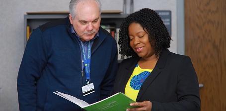 African American Woman and White Man looking at a green folder