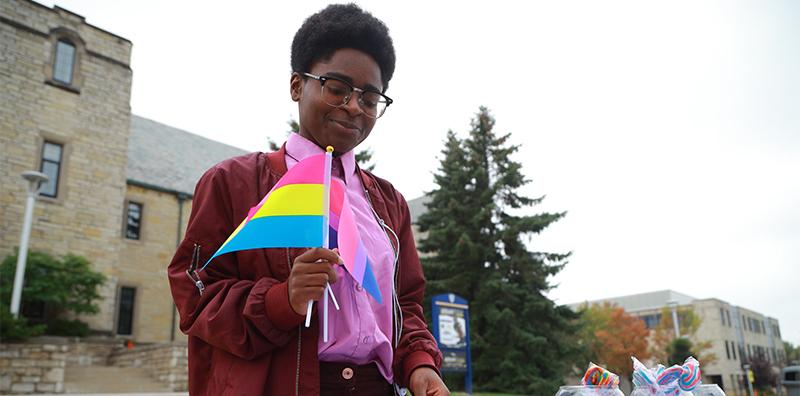 Student holding bisexual and pansexual flags